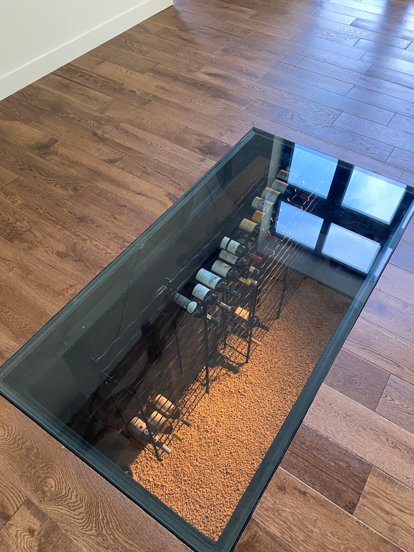 Cave à vin aménagée sous une dalle vitrée dans le salon
